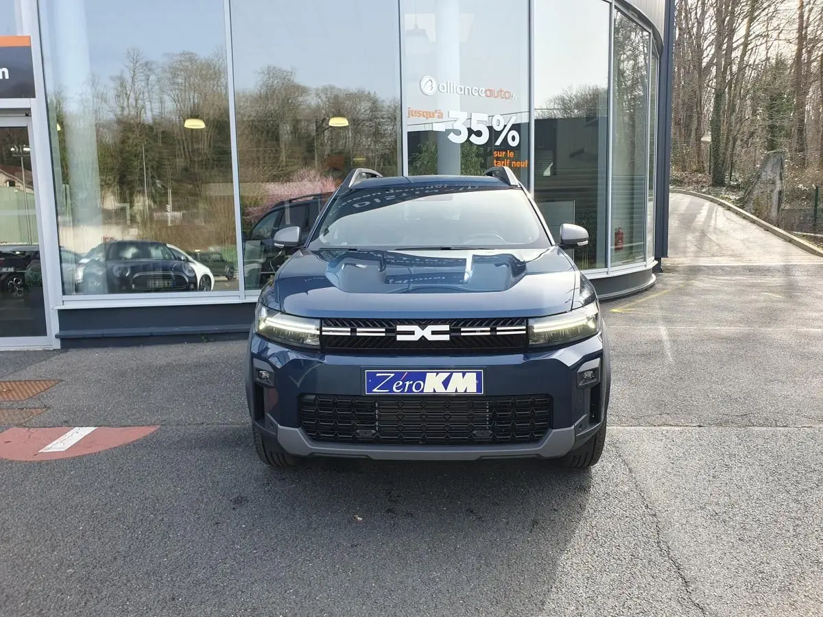 Vue frontale d’un Dacia Bigster bleu indigo avec signature lumineuse LED et toit panoramique visible.