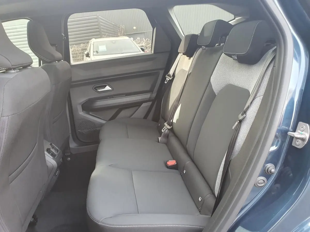 Vue intérieure arrière côté droit du Dacia Bigster bleu indigo, montrant la banquette 3 places avec ceintures et appuie-têtes.