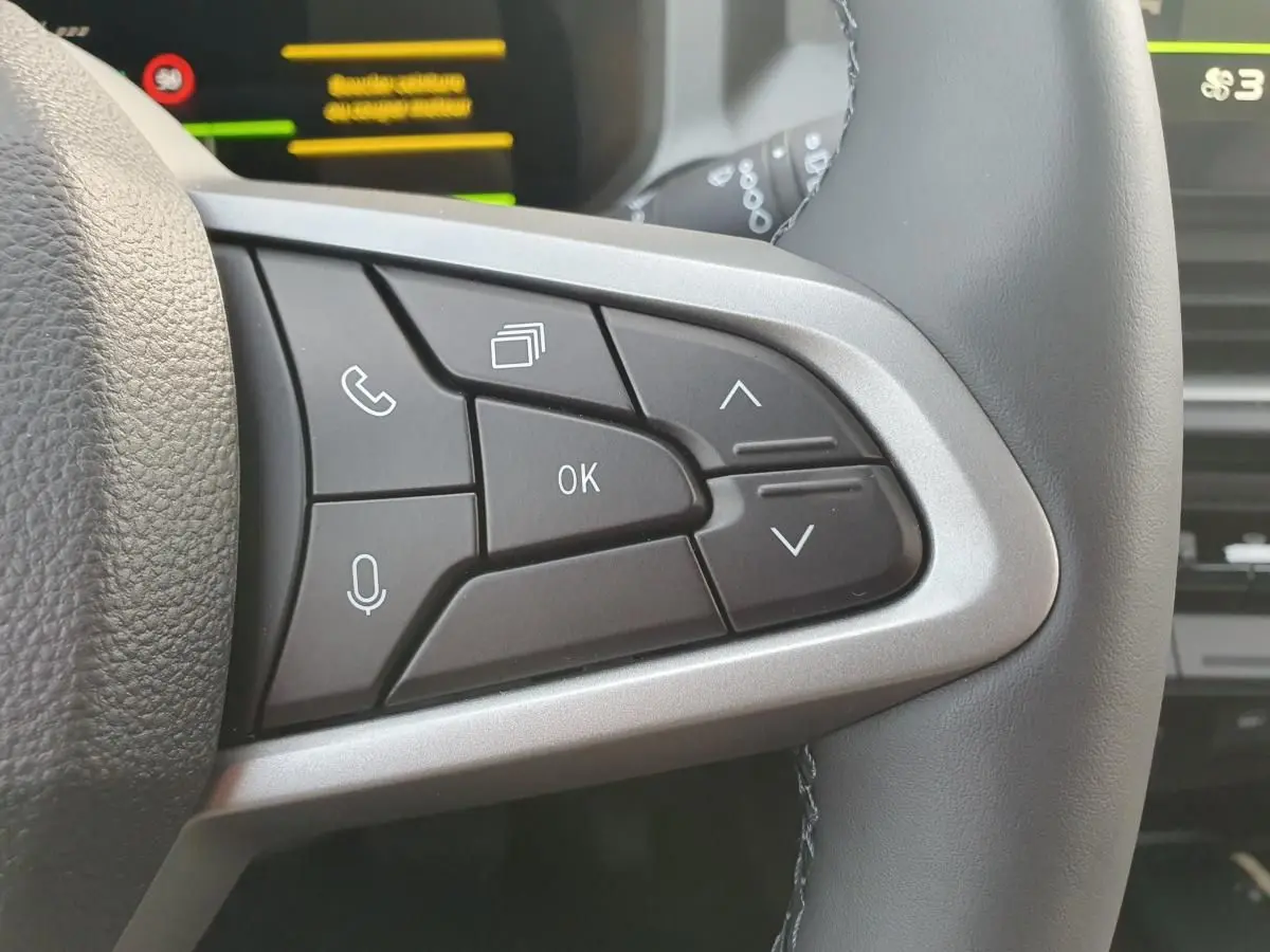 Gros plan sur les commandes multifonctions à droite du volant du Dacia Bigster, boutons noirs et contour argenté.