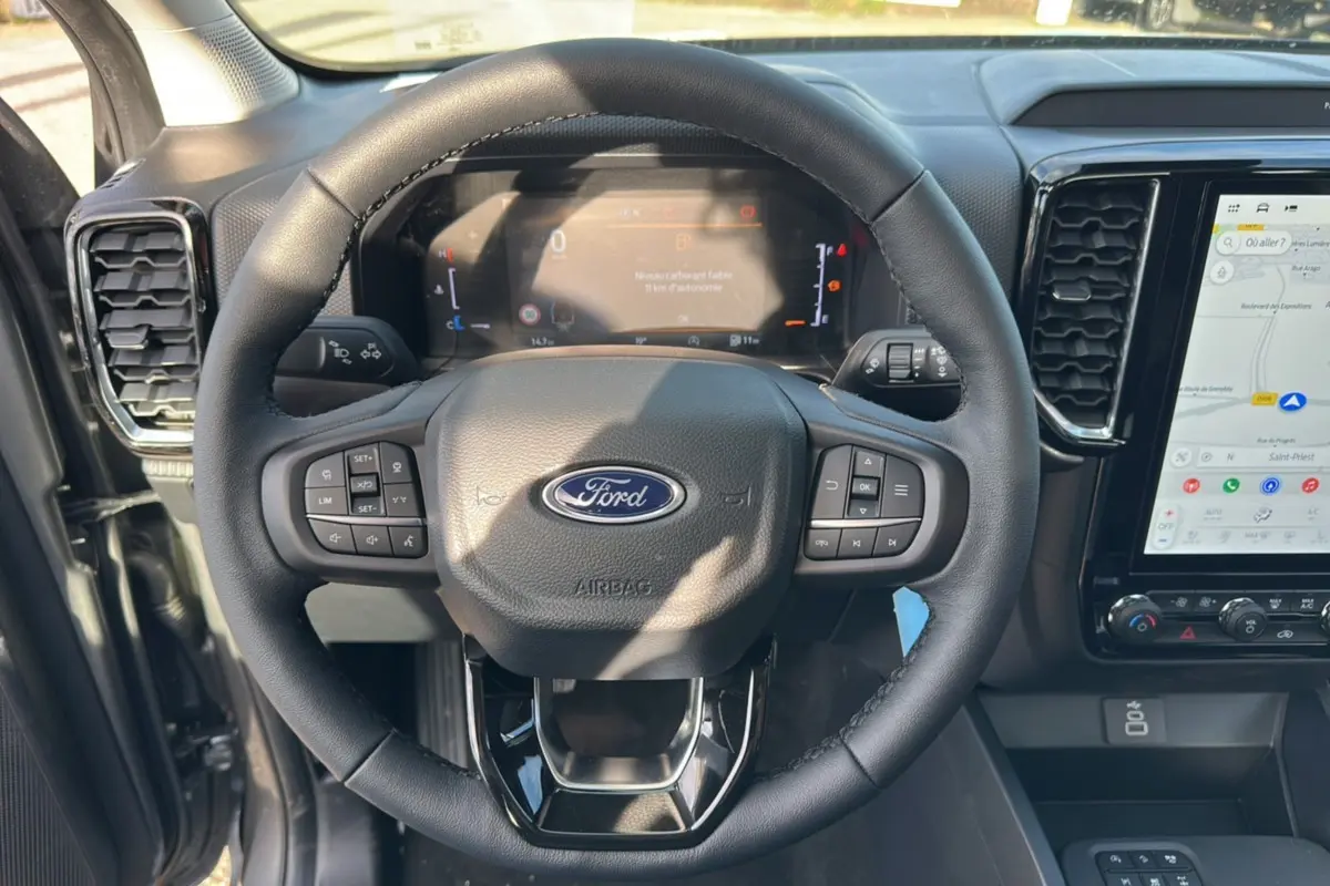 Vue intérieure centrée sur le volant cuir multifonctions du Ford Ranger gris carbone avec écran tactile et tableau de bord numérique.