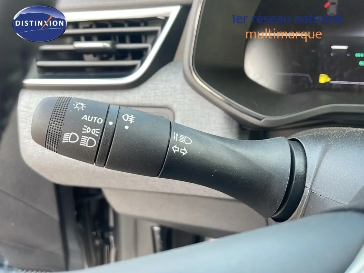 Gros plan sur la commande des phares et clignotants à gauche du volant dans l’habitacle gris d’une Renault Clio 2025.