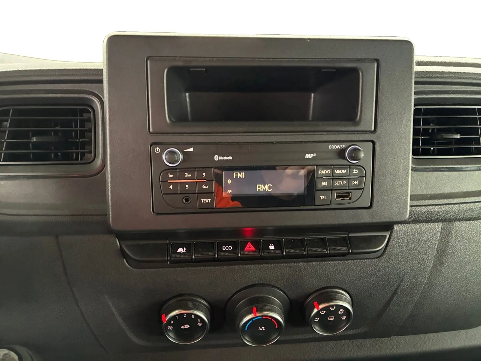 Tableau de bord du Renault Master 2024 avec radio Bluetooth, commandes climatisation manuelle et boutons fonctionnels en vue frontale.