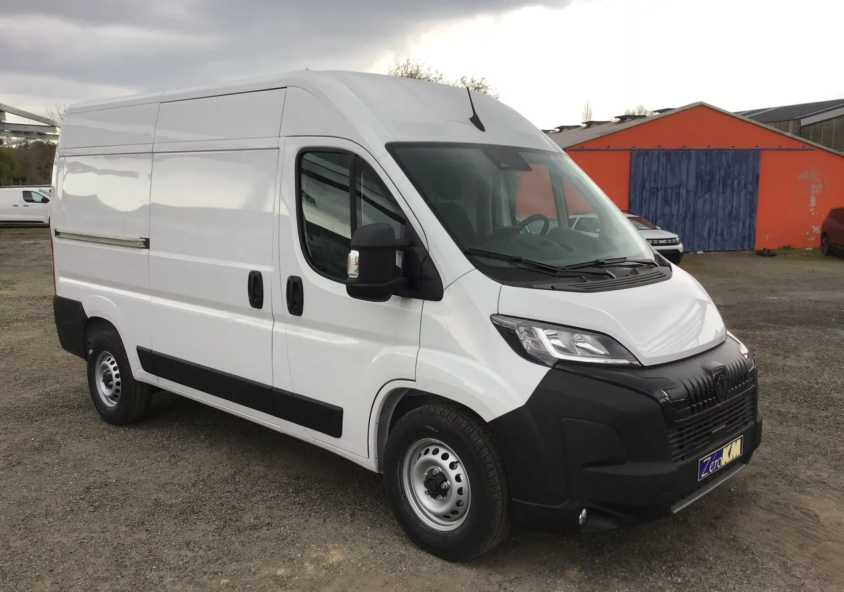 Vue 3/4 avant droit d'un Peugeot Boxer Fourgon blanc 2025 avec pare-chocs noir et jantes acier.
