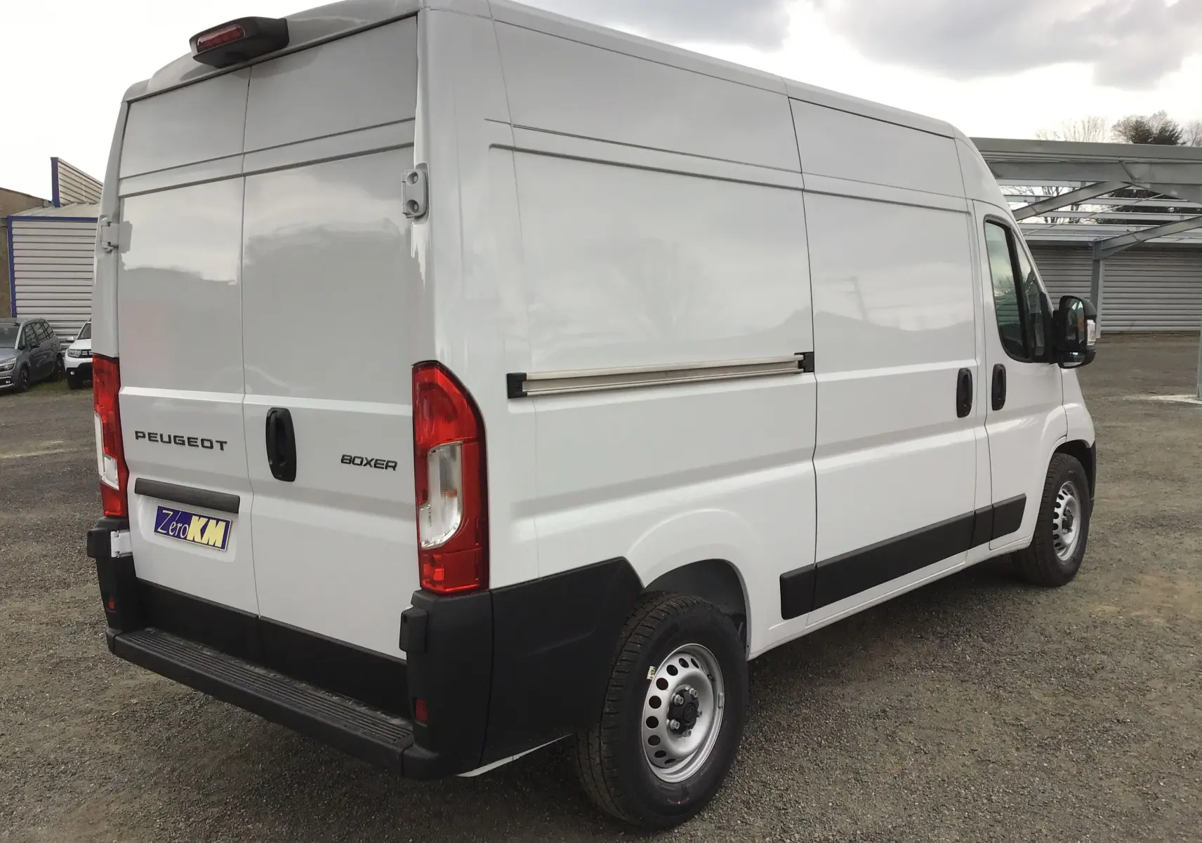 Vue 3/4 arrière droite d'un utilitaire Peugeot Boxer blanc avec portes arrière battantes et protections noires.