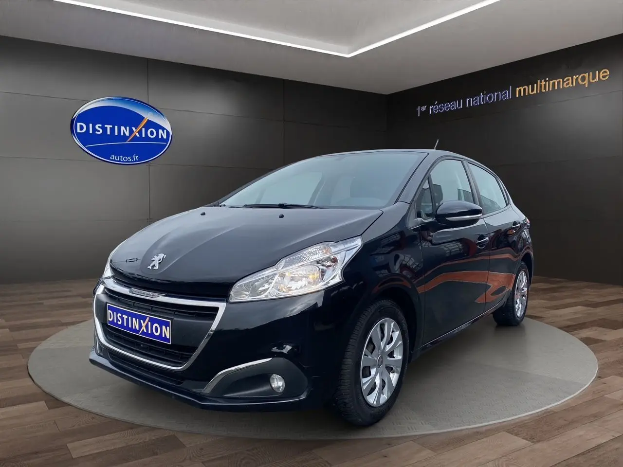 Peugeot 208 Affaire noir vue 3/4 avant droit, avec calandre chromée et feux allumés en intérieur showroom.