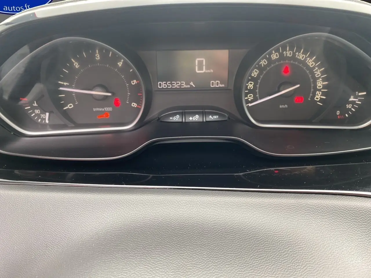 Vue rapprochée du tableau de bord de la Peugeot 208 Affaire noir, affichant le compteur et l'odomètre à 65323 km.