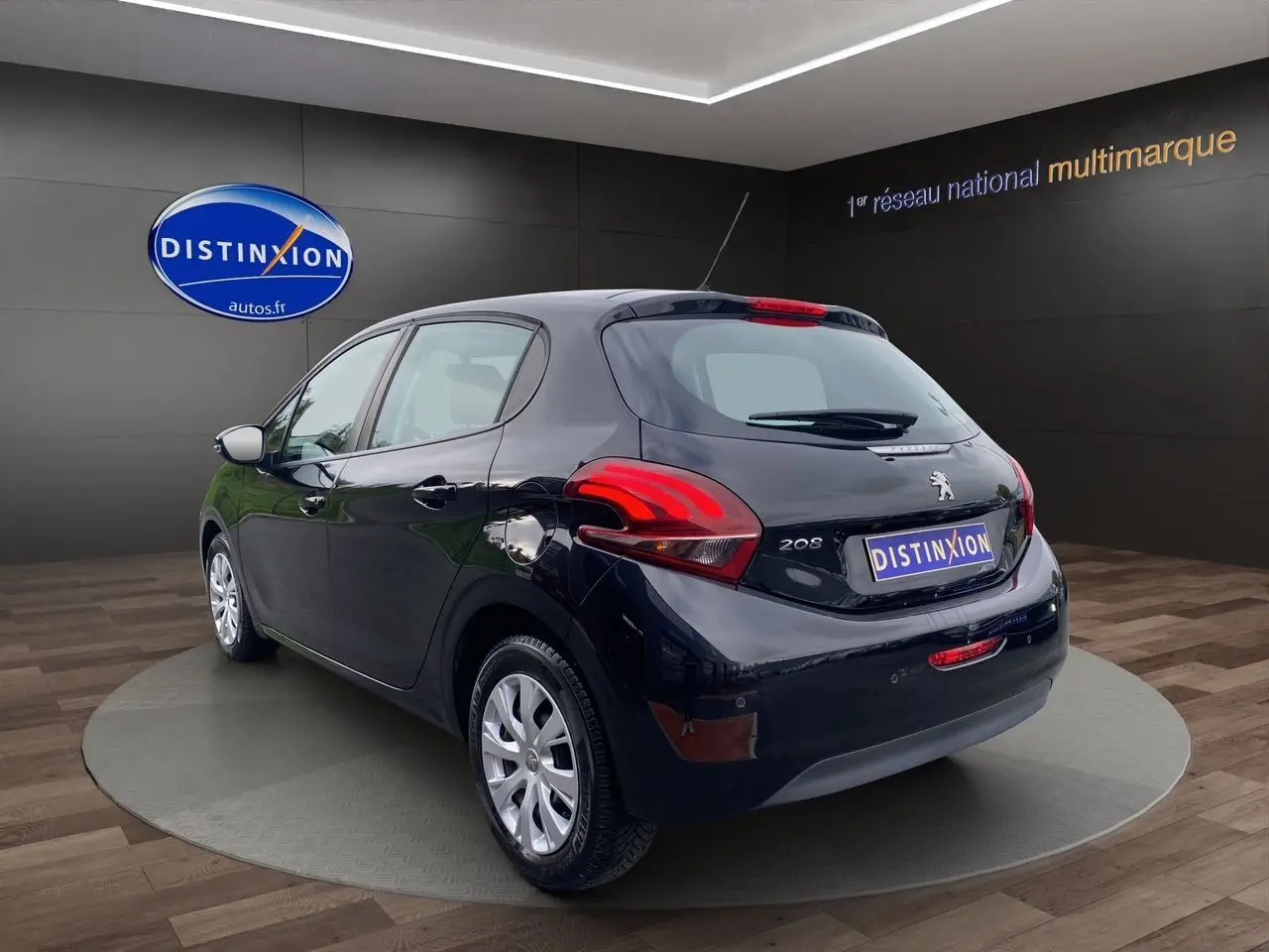 Vue 3/4 arrière droite d'une Peugeot 208 Affaire Premium Pack noire de 2019 avec radar de recul en showroom.