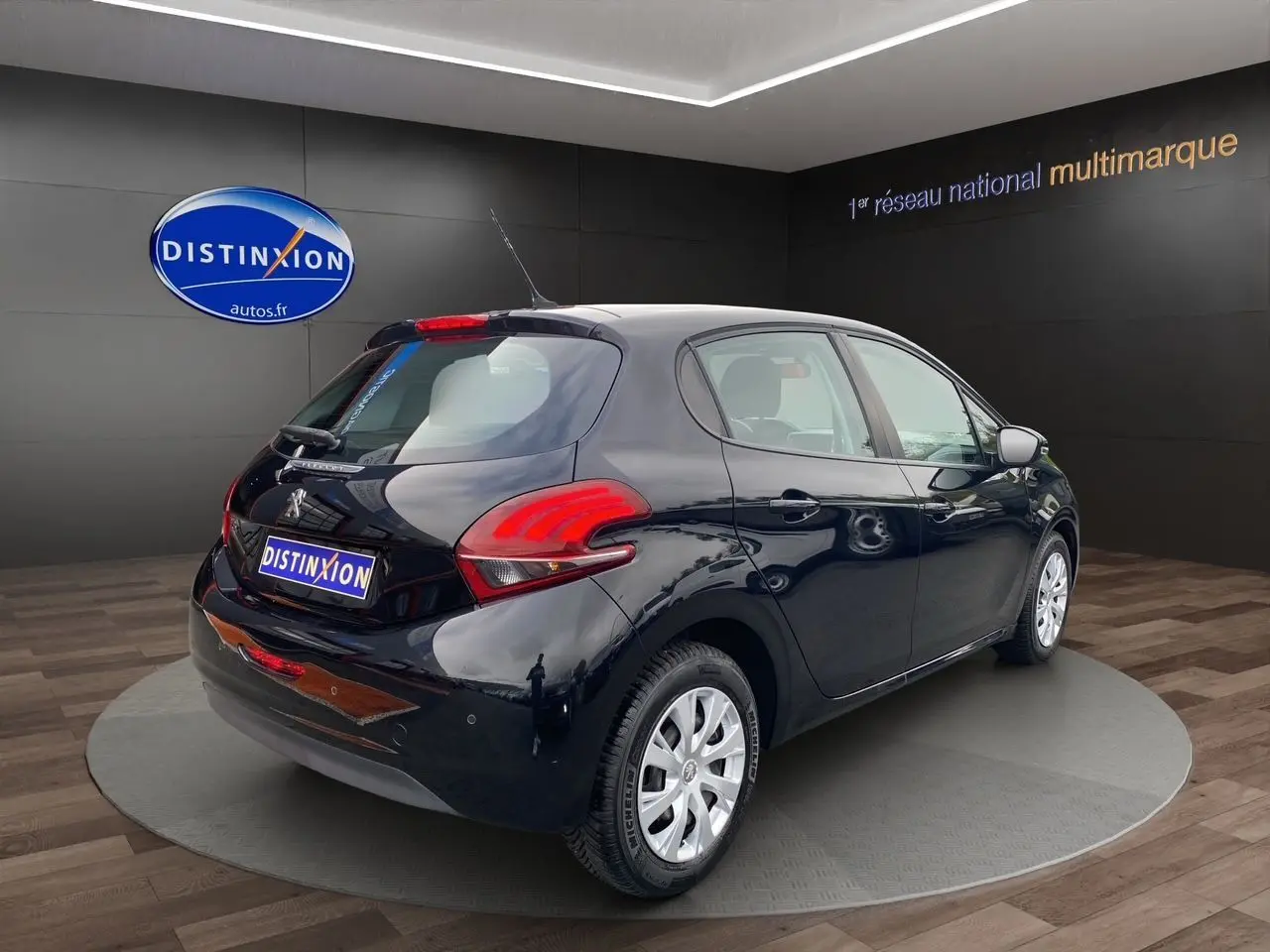 Peugeot 208 Affaire noir vue 3/4 arrière droit en intérieur, avec feux arrière rouges et jantes argentées.