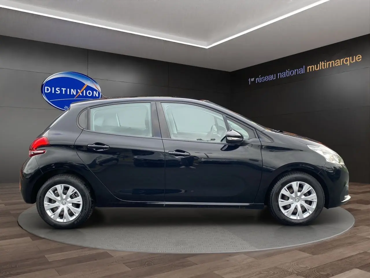Profil latéral droit d'une Peugeot 208 Affaire Premium Pack noire, cinq portes, en intérieur showroom.