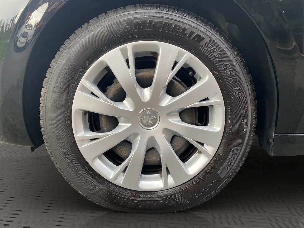 Gros plan sur la roue avant gauche d'une Peugeot 208 Affaire noire, avec jante en alliage et pneu Michelin visible.