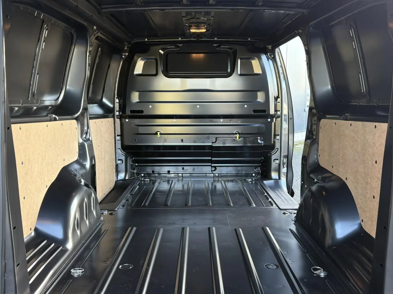 Vue intérieure arrière du Citroën Jumpy XL gris titane, montrant l'espace de chargement avec cloison tôlée et anneaux d'arrimage.
