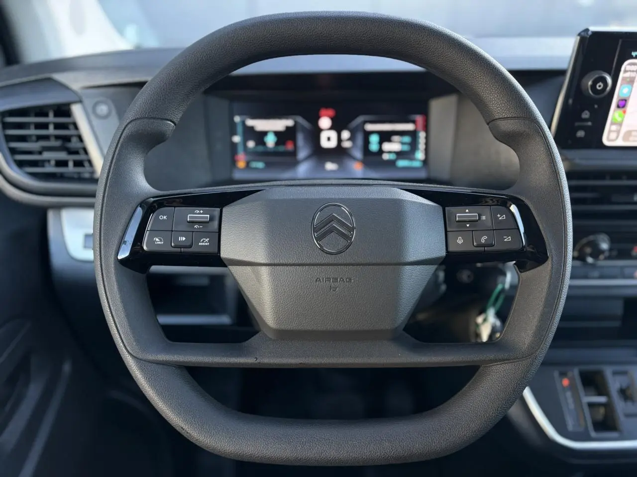 Volant noir Citroën Jumpy XL 2025 avec commandes intégrées, tableau de bord numérique et écran tactile visible en arrière-plan.