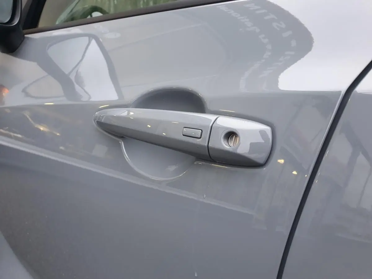 Poignée de porte côté gauche gris céramique du Nissan Juke 2025 avec bouton de verrouillage intégré.