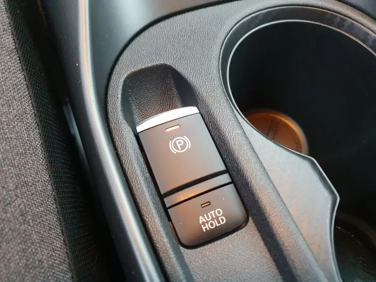 Gros plan sur le frein à main électrique avec fonction Auto Hold et porte-gobelets du Nissan Juke gris céramique 2025.