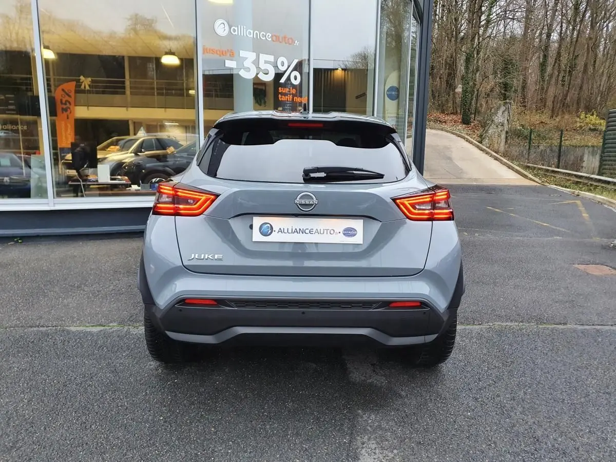 Vue arrière d'un Nissan Juke gris céramique 2025 avec feux LED allumés et vitrage arrière teinté.