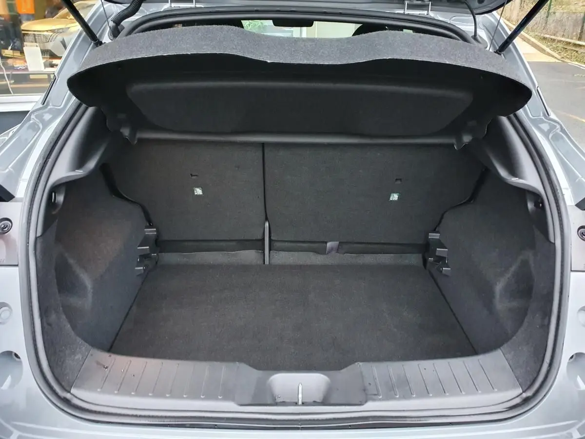 Coffre ouvert vu de l'arrière d'un Nissan Juke gris céramique, montrant l'espace de chargement et la banquette rabattable.