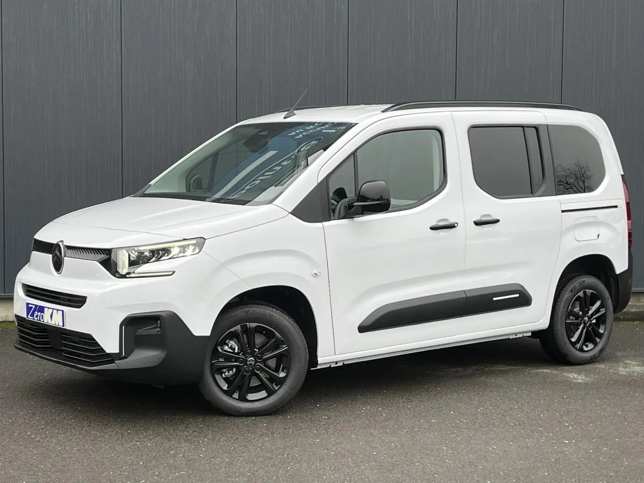 Vue 3/4 avant droite d'un Citroën Berlingo Multispace blanc Glacier avec jantes noires et barres de toit.