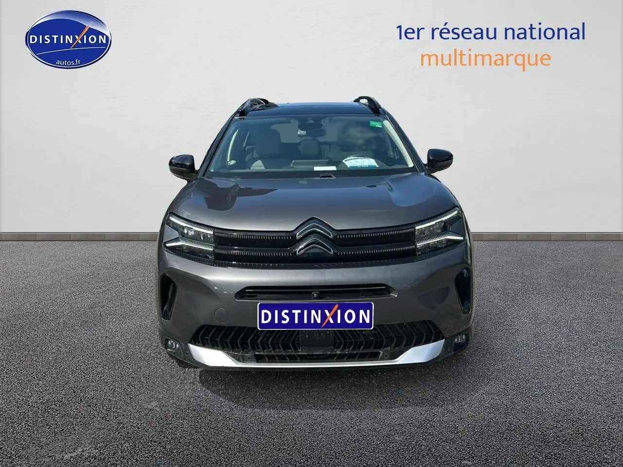 Vue avant d'un Citroën C5 Aircross gris platinium avec calandre distinctive et barres de toit visibles.