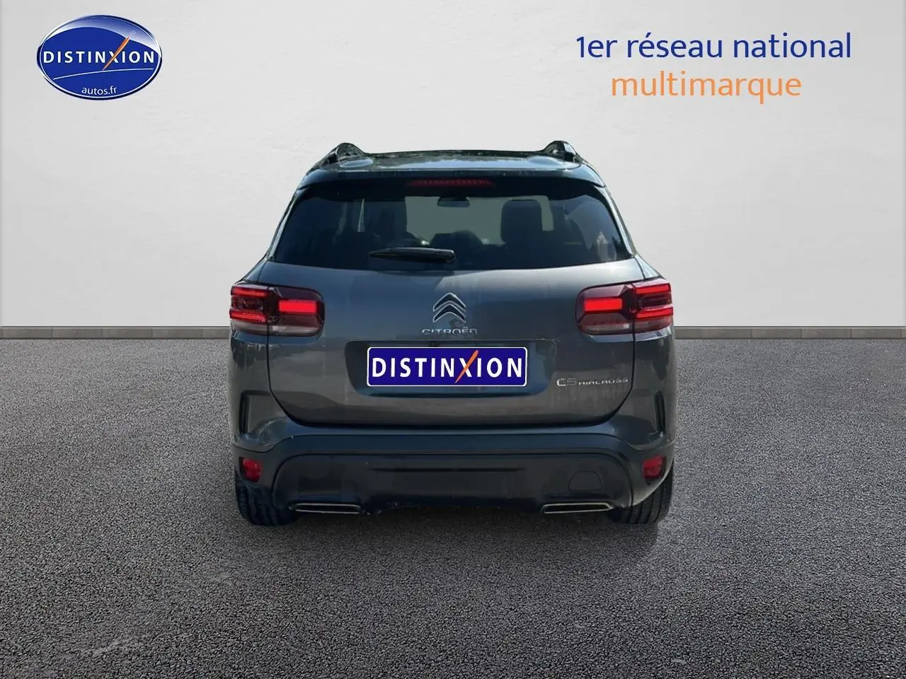 Vue arrière d'un Citroën C5 Aircross gris platinium avec feux arrière LED et barres de toit visibles.