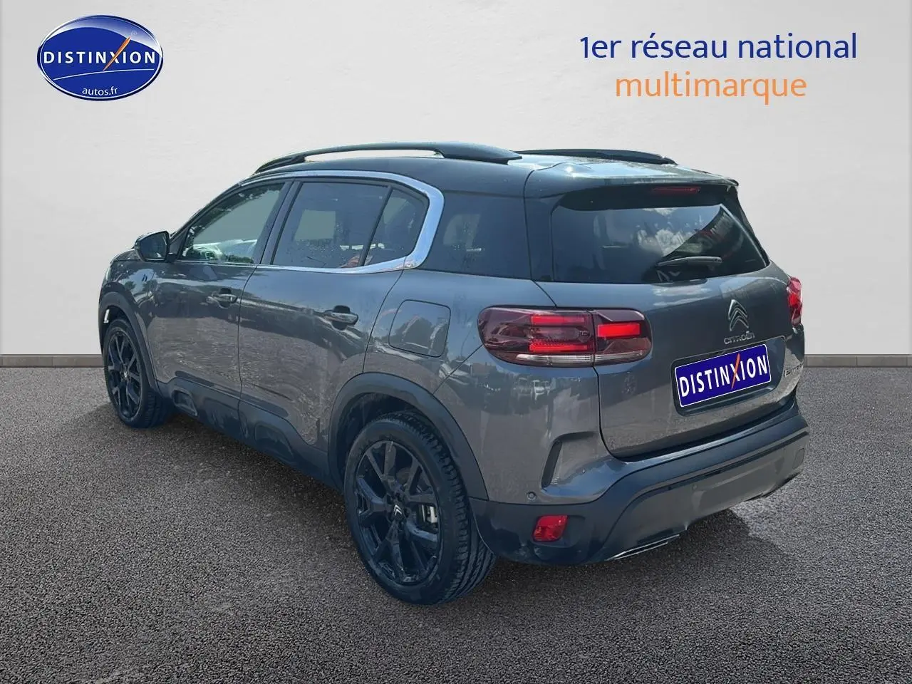 Vue 3/4 arrière droite du Citroën C5 Aircross gris platinium avec barres de toit et jantes noires.