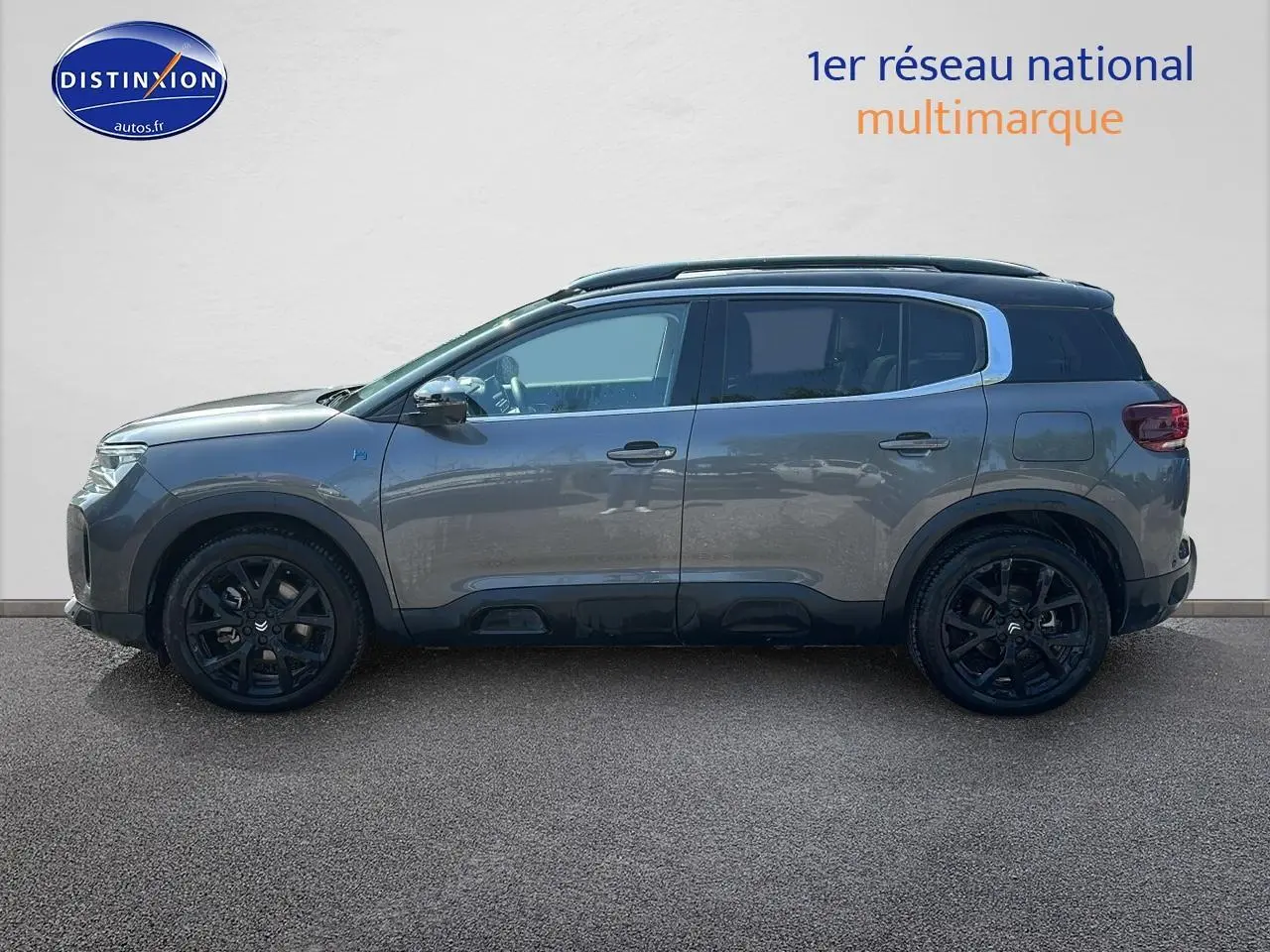 Vue de profil côté gauche d’un Citroën C5 Aircross gris platinium avec jantes noires et barres de toit.