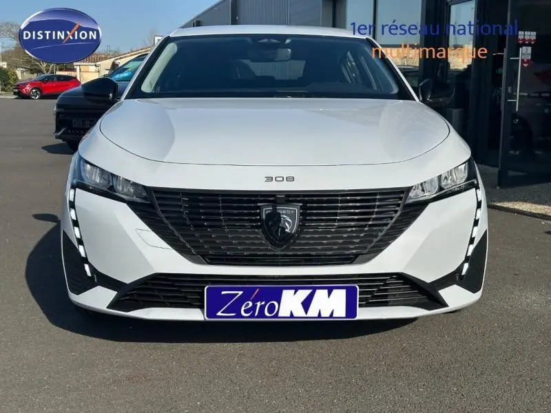 Vue de face d'une Peugeot 308 blanche avec calandre noire et feux LED distinctifs en forme de griffes.