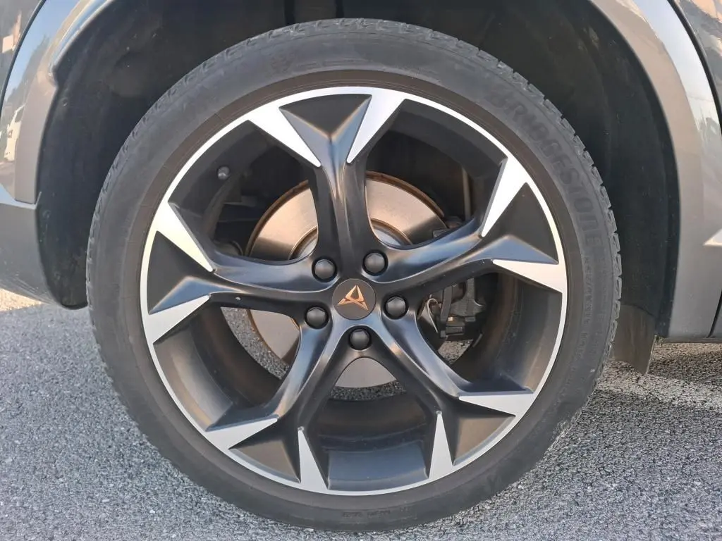 Gros plan sur la roue avant droite d'une CUPRA Formentor gris foncé, jante alliage noire et argentée au design sportif.