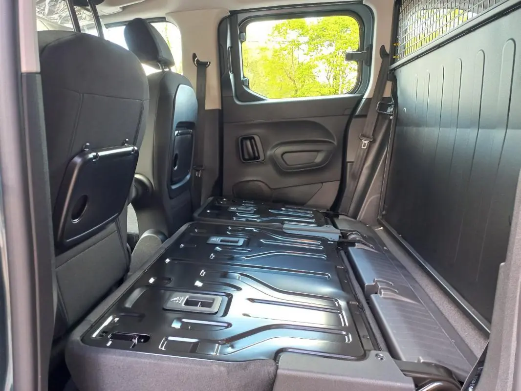 Vue intérieure côté droit du coffre d’un Opel Combo Life Elegance M 2025 bleu avec banquette arrière rabattue et espace de chargement plat.