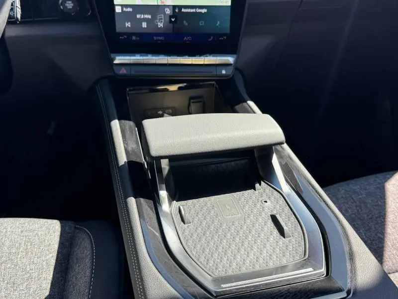 Vue rapprochée de la console centrale avec accoudoir et écran tactile du Renault Austral rouge 2025 hybride.