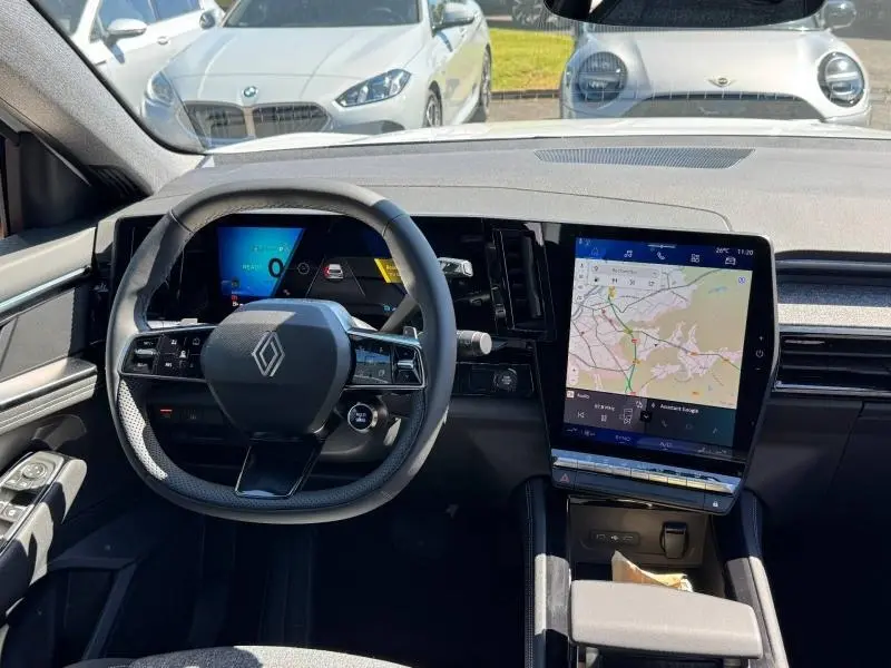 Vue intérieure du tableau de bord du Renault Austral rouge 2025, avec écran tactile central affichant un GPS.