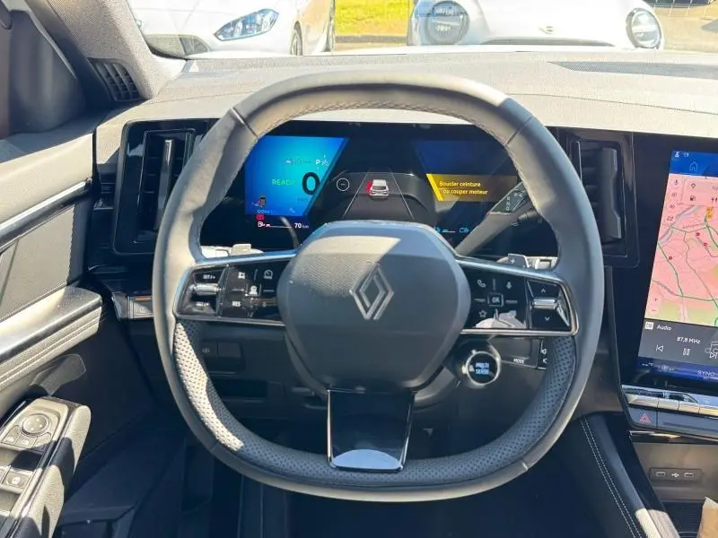 Vue intérieure centrée sur le volant multifonction noir du Renault Austral 2025 avec tableau de bord numérique et écran tactile latéral.