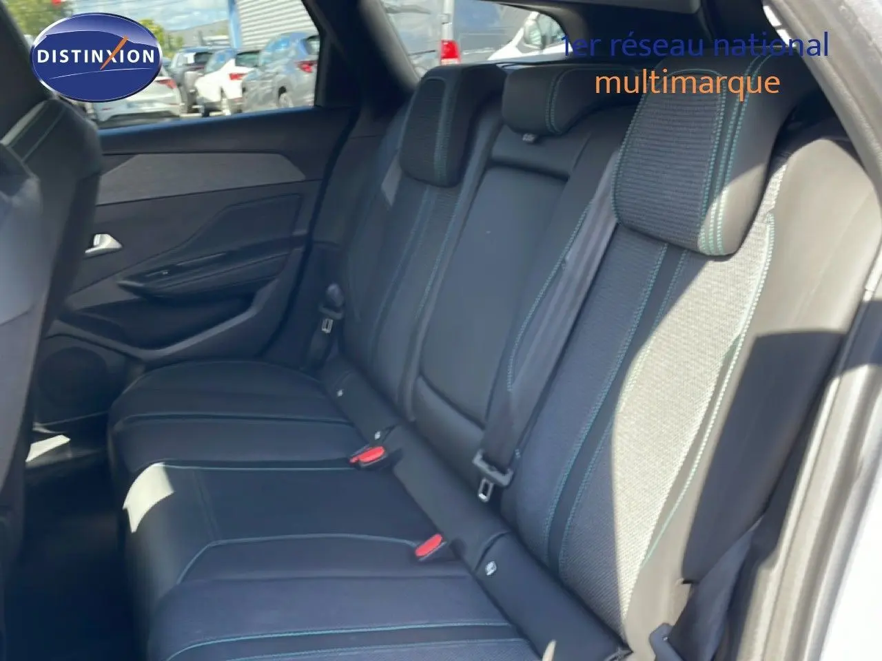 Vue intérieure sur la banquette arrière en tissu et cuir gris noir avec surpiqûres bleues d'une Peugeot 308 SW 2025.