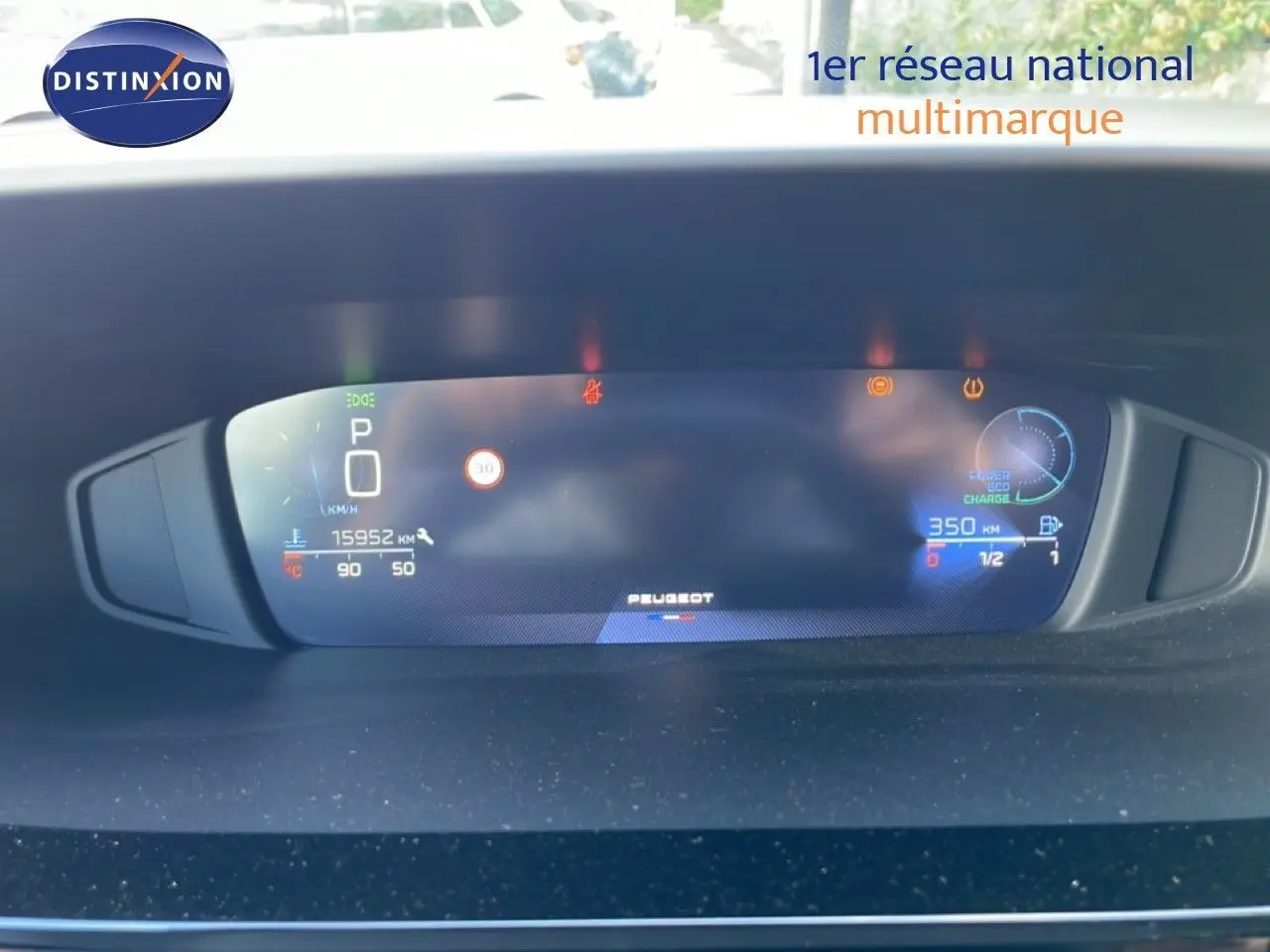 Tableau de bord numérique de Peugeot 308 SW gris, affichant vitesse, autonomie et indicateurs, vue frontale rapprochée.