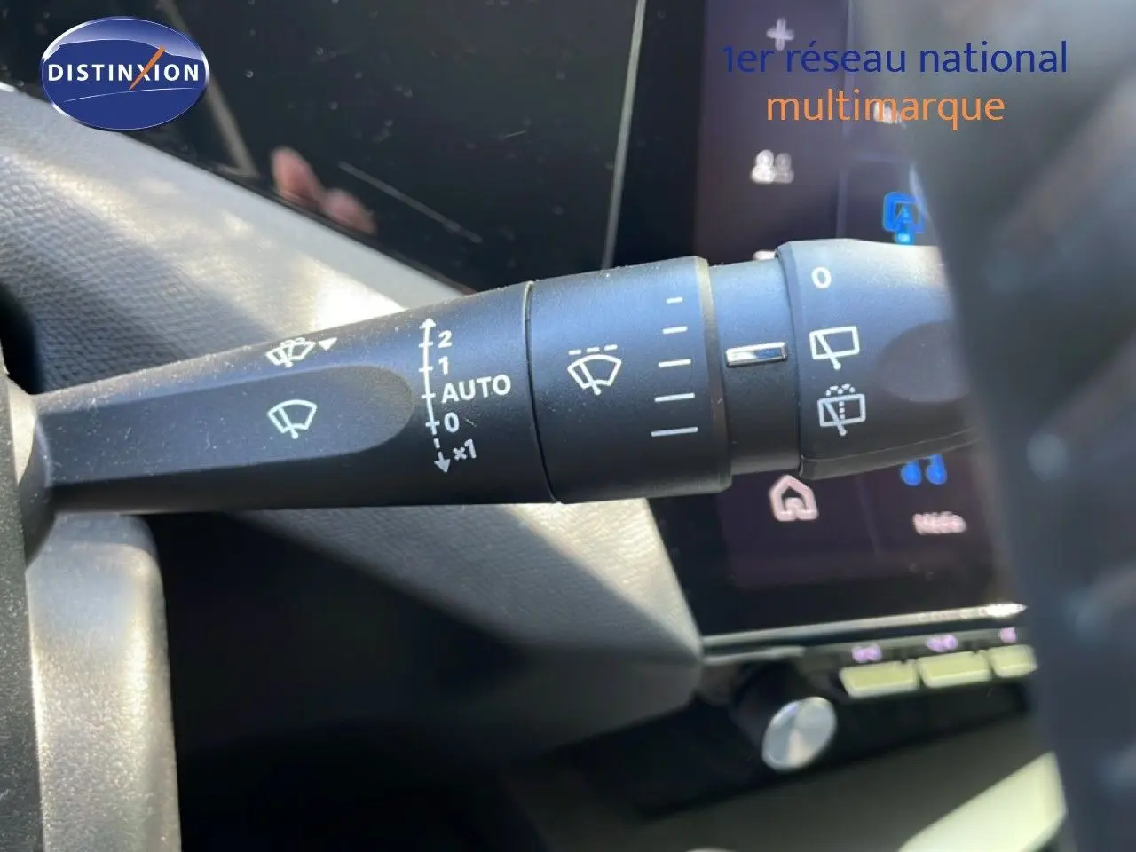 Gros plan sur la commande des essuie-glaces dans l’habitacle du Peugeot 308 SW gris Artense, avec écran tactile en arrière-plan.