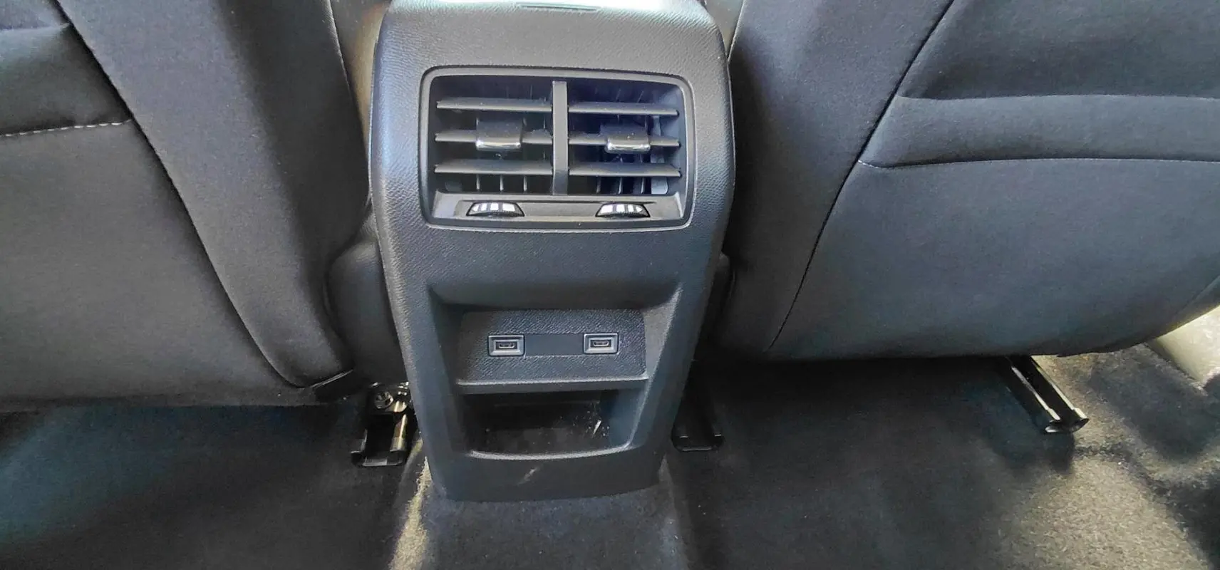 Vue rapprochée de la console arrière avec bouches d’aération et ports USB dans une Peugeot 308 Hybrid 145 gris.