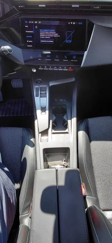 Vue intérieure centrée sur la console centrale et l'écran tactile du Peugeot 308 Hybrid gris avec accoudoir central.