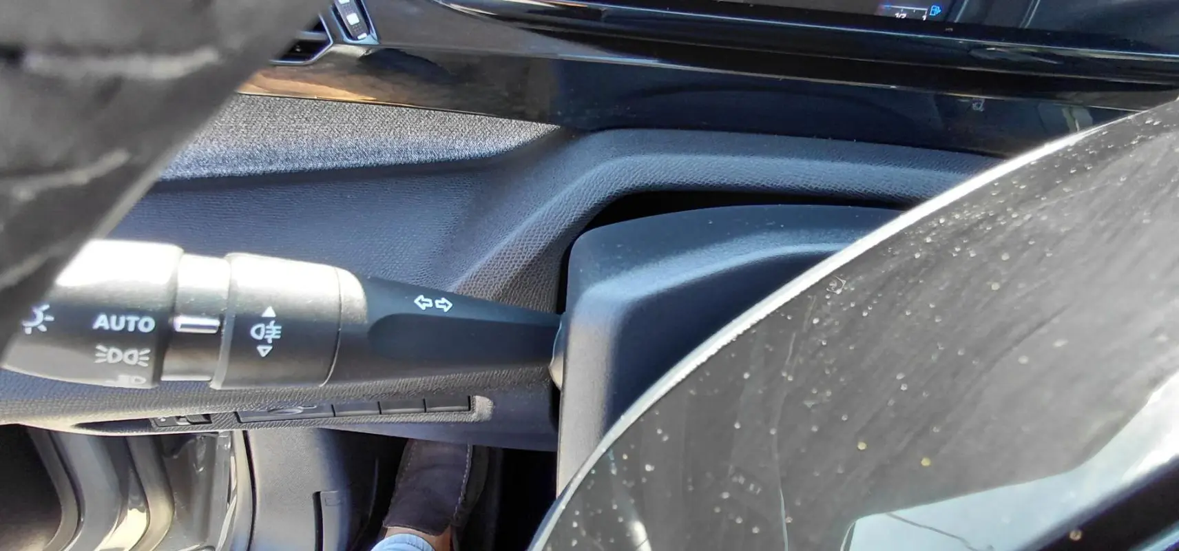 Détail de la commande des feux et clignotants côté gauche du volant dans l’habitacle d’une Peugeot 308 Hybrid 145 gris.