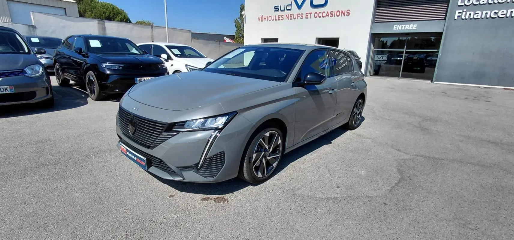 Peugeot 308 Hybrid gris vue 3/4 avant droit, avec jantes alliage 17 pouces et calandre noire distinctive.