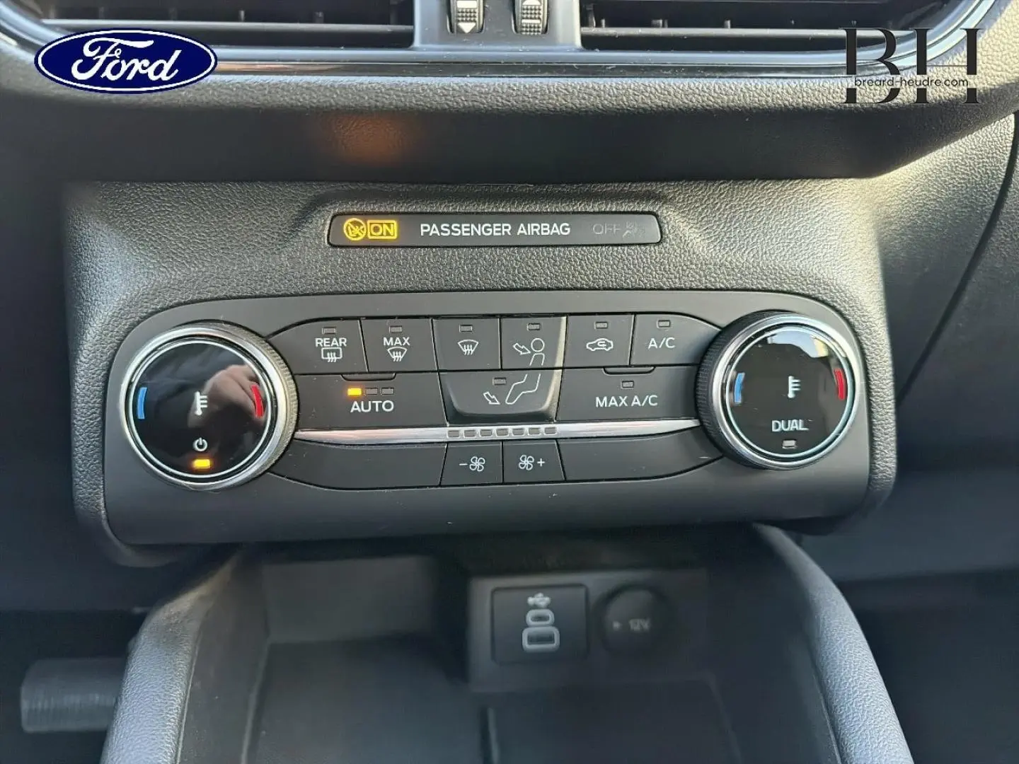 Gros plan sur la console centrale du Ford Kuga 2023, montrant les commandes de climatisation bi-zone et les voyants actifs.