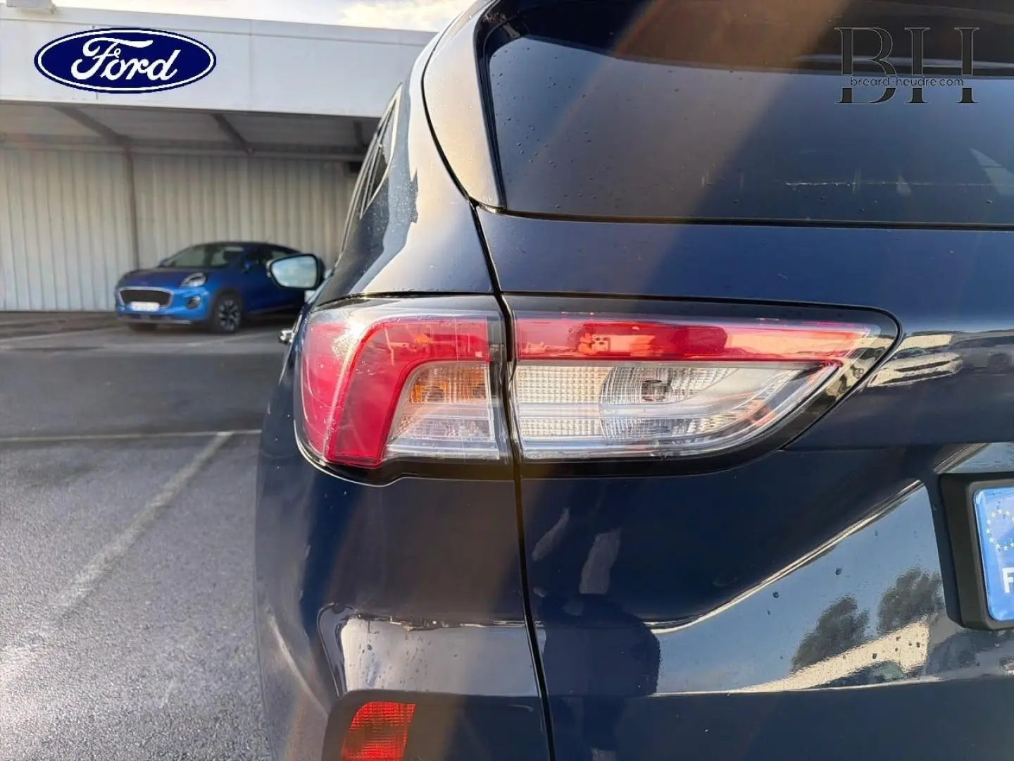 Vue arrière droite du Ford Kuga bleu avec feux arrière LED et becquet distinctif visible.