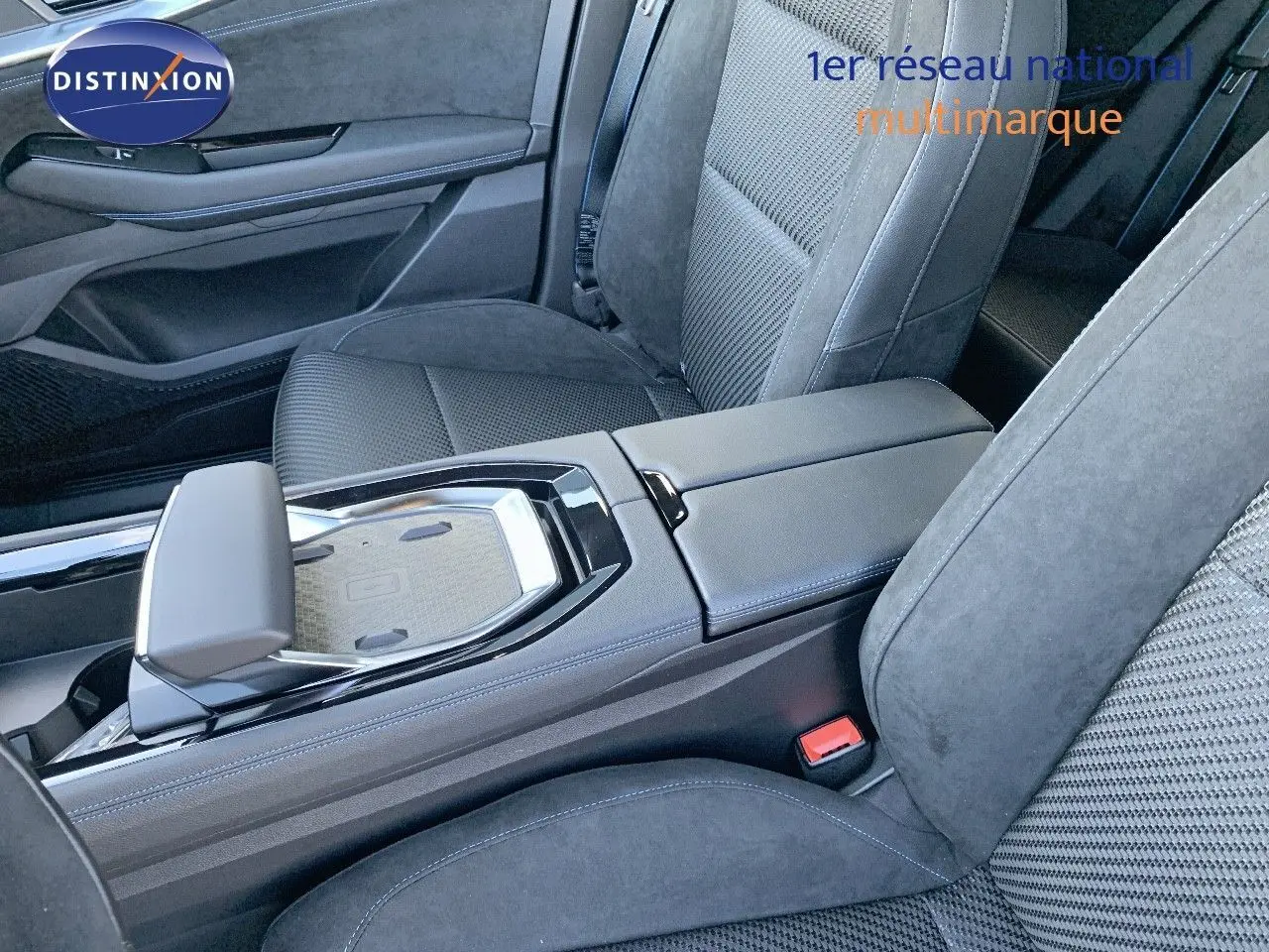 Vue intérieure centrée sur la console centrale et sièges avant en tissu noir du Renault Austral 2024 hybride.