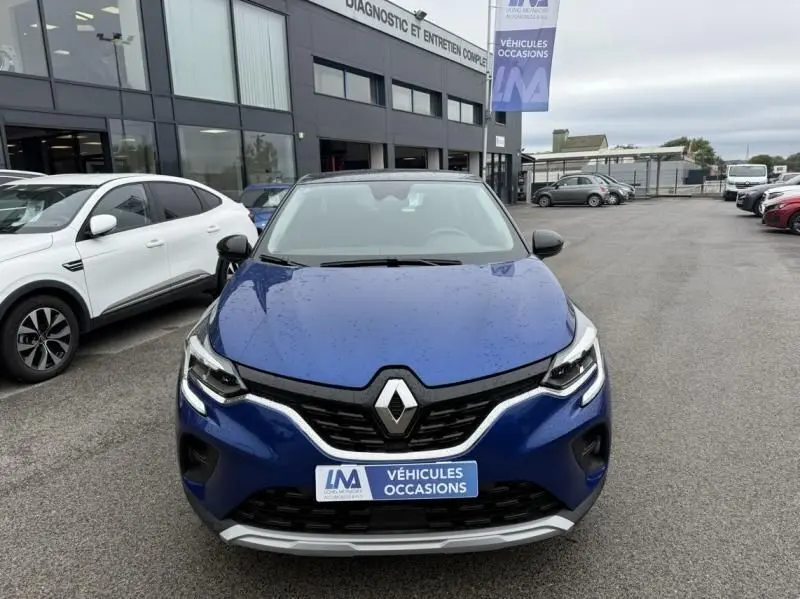 Vue frontale d'un Renault Captur E-Tech 145 Zen bleu métal 2022 avec logo Renault et plaque "Véhicules Occasions" visible.