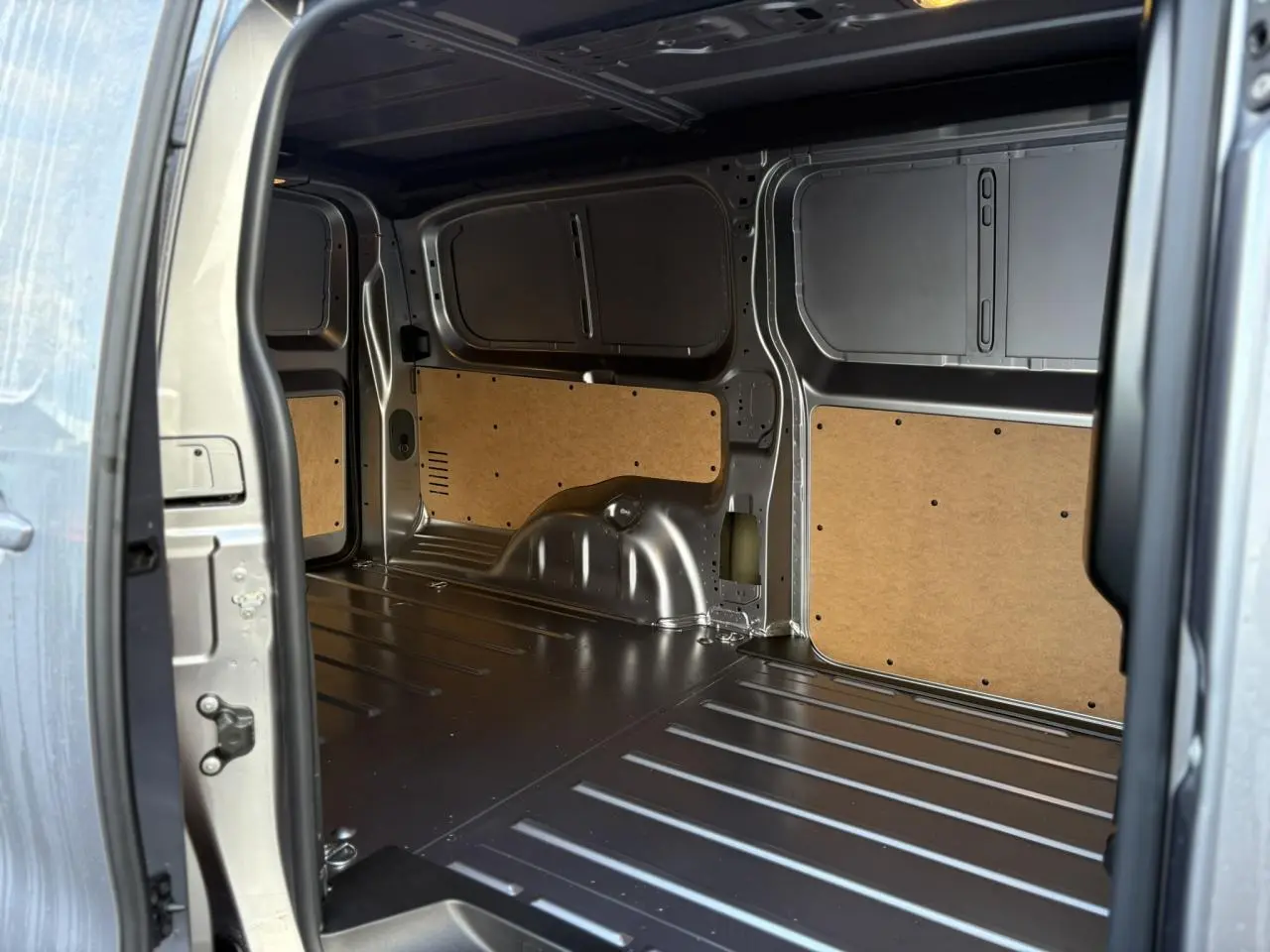 Intérieur de la zone de chargement du Citroën Jumpy XL gris Artense, vue depuis la porte latérale ouverte.