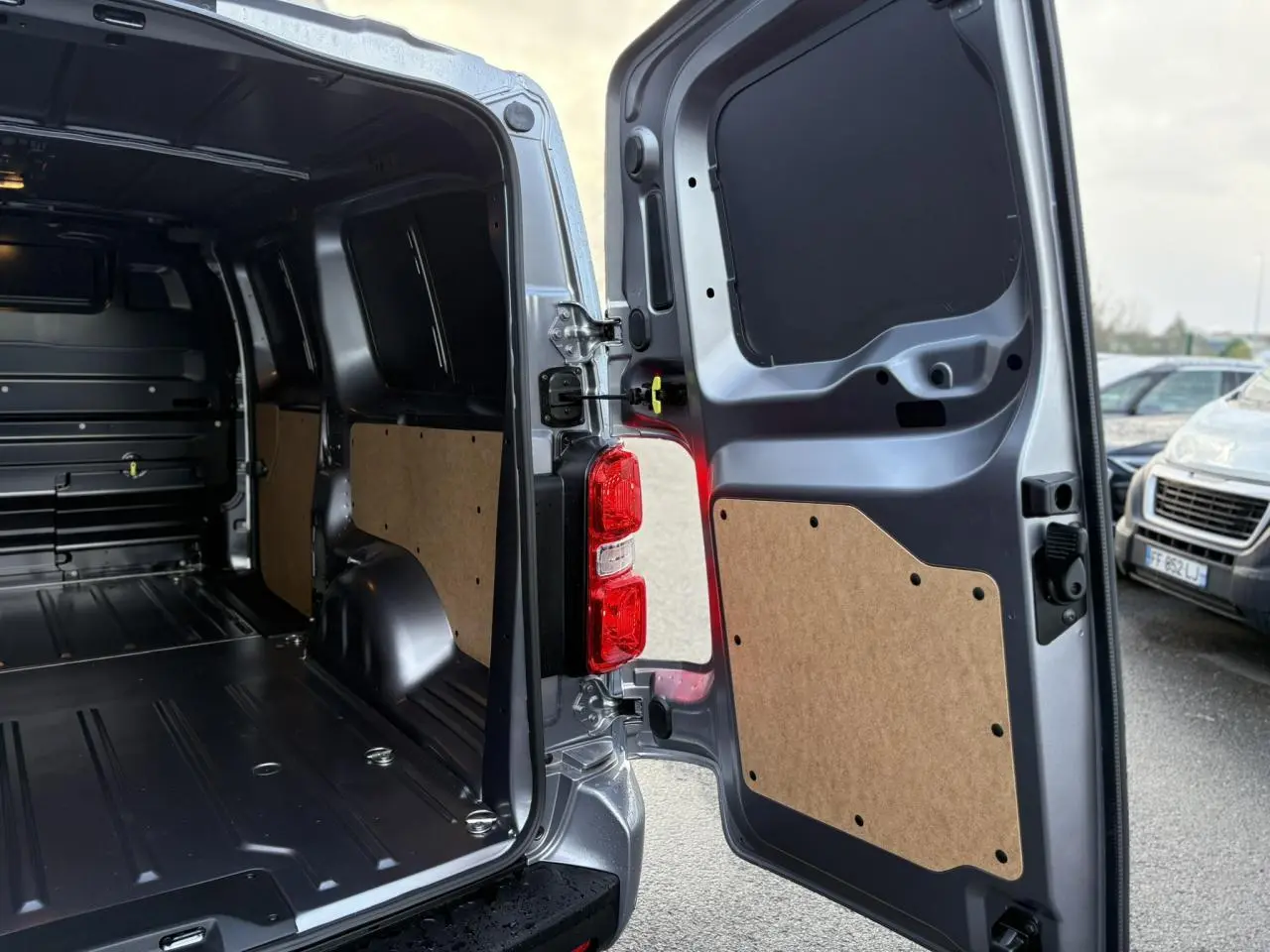Vue arrière ouverte du Citroën Jumpy XL gris Artense, montrant l'intérieur utilitaire avec panneaux de protection en bois.