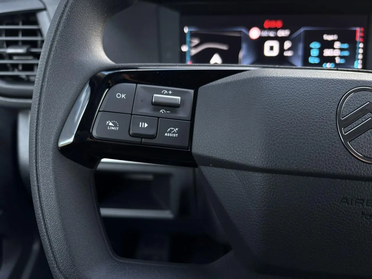 Gros plan sur le volant noir du Citroën Jumpy 2025, montrant les commandes de régulateur et l'affichage numérique flou.