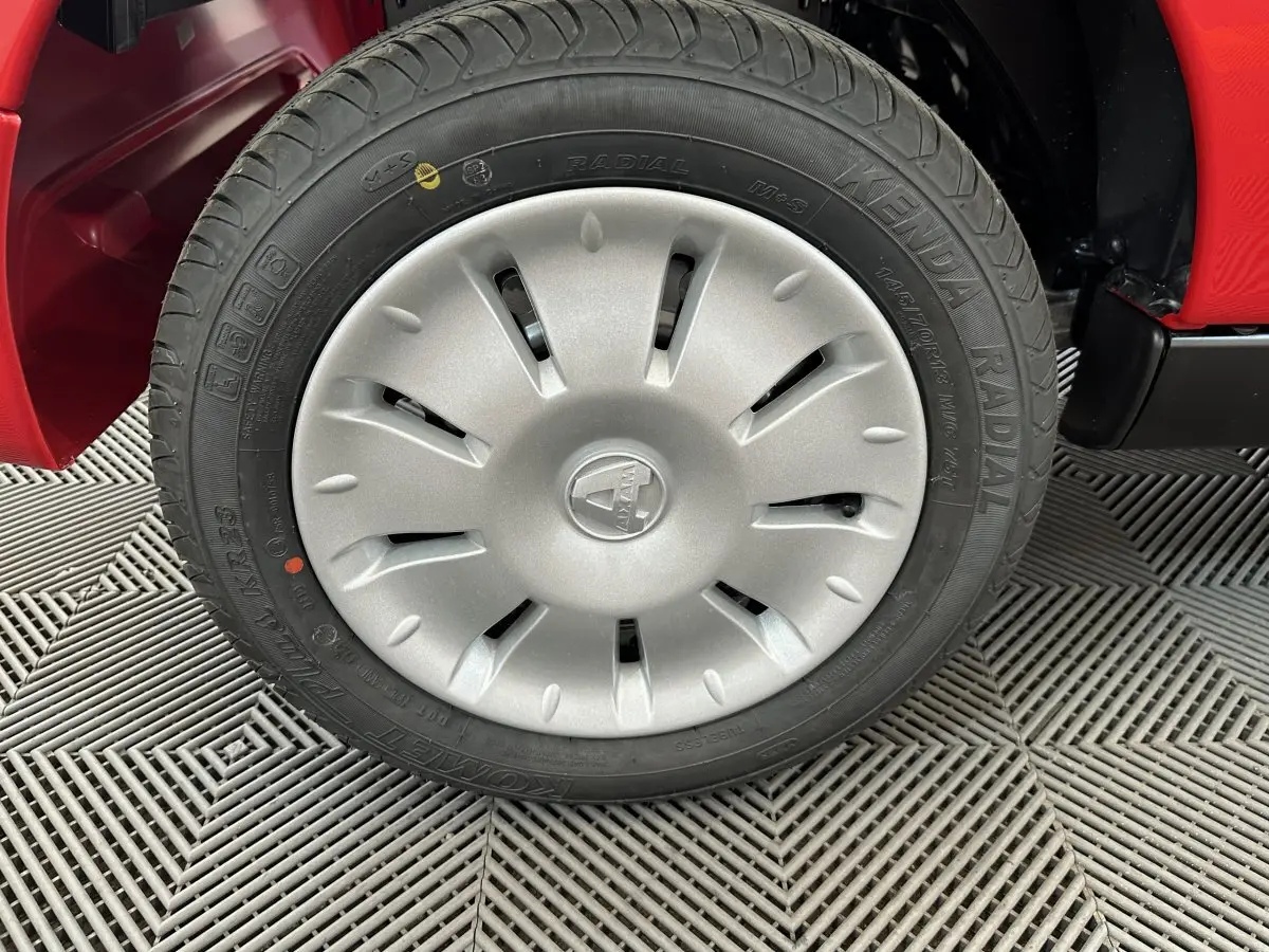 Gros plan sur la roue avant gauche de l'AIXAM Ambition E City Pack rouge 2025 avec enjoliveur gris et pneu radial.