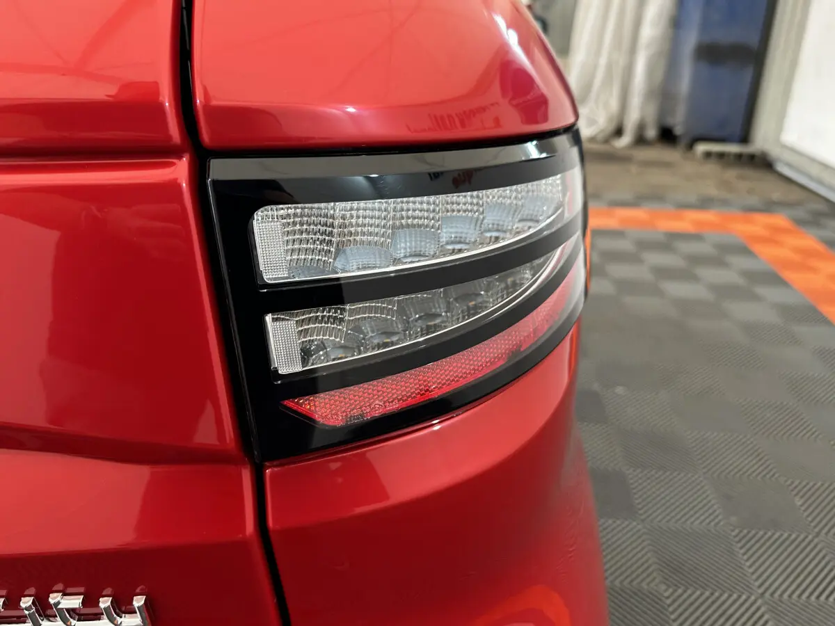 Gros plan sur le feu arrière droit rouge brillant de l'AIXAM AMBITION E CITY PACK 2025 avec détails LED et carrosserie lisse.