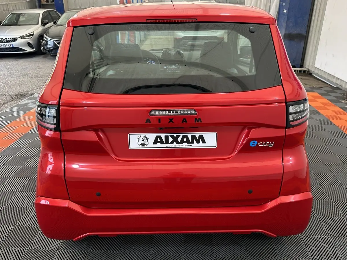 Vue arrière d'une AIXAM AMBITION E CITY PACK rouge électrique 2025 avec logo e-city et feux LED distinctifs.