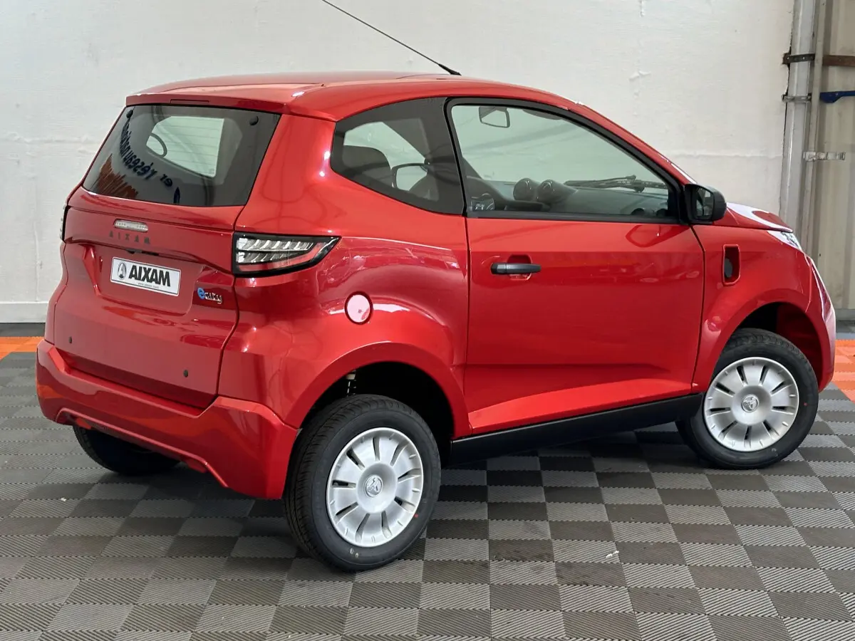 Vue 3/4 arrière droite d'une Aixam Ambition E City Pack rouge 2025 avec caméra sur rétroviseur côté conducteur.