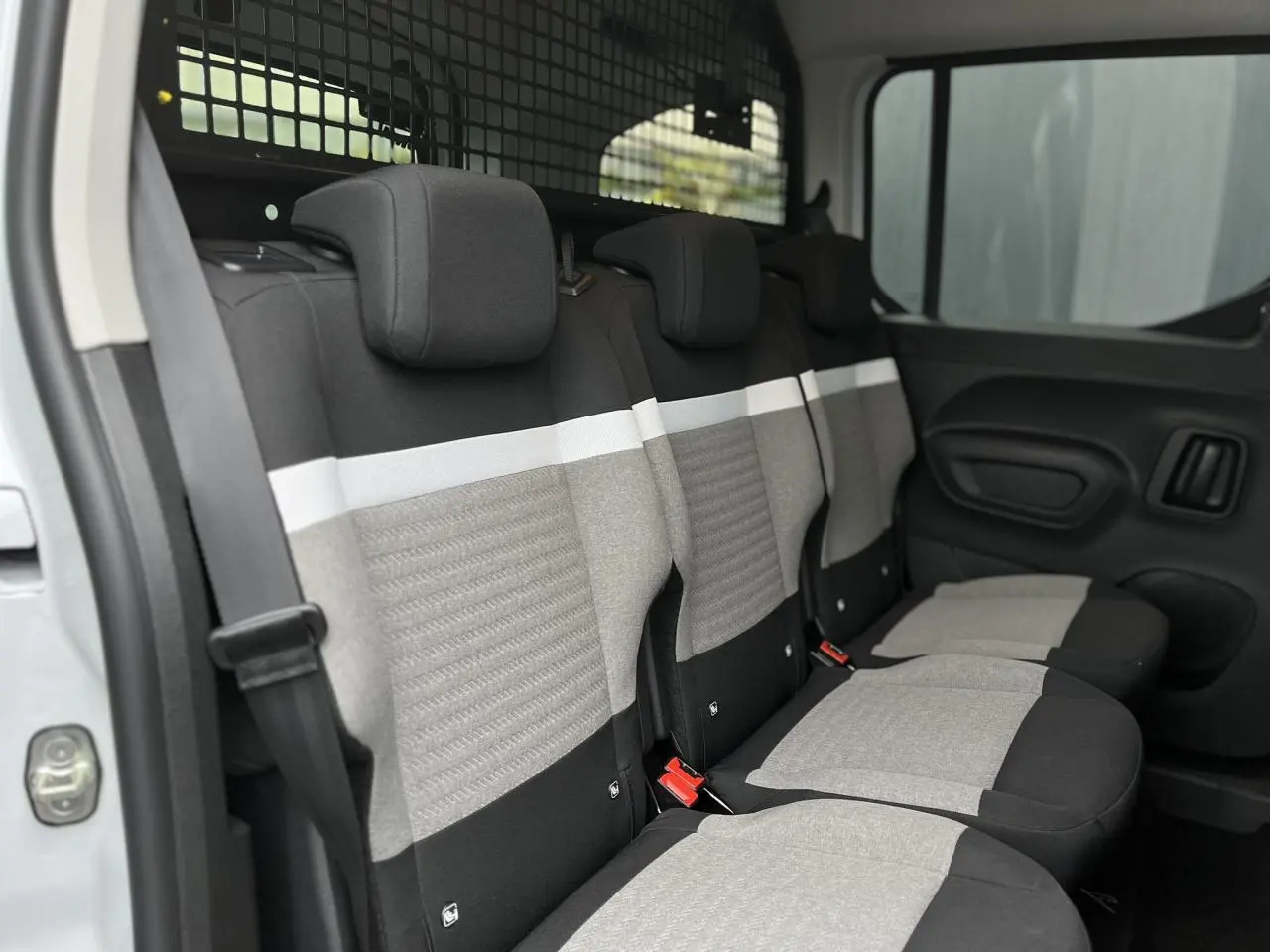 Vue intérieure côté droit des sièges arrière gris et noirs du Citroën Berlingo Multispace blanc glacier avec lunette ouvrante.